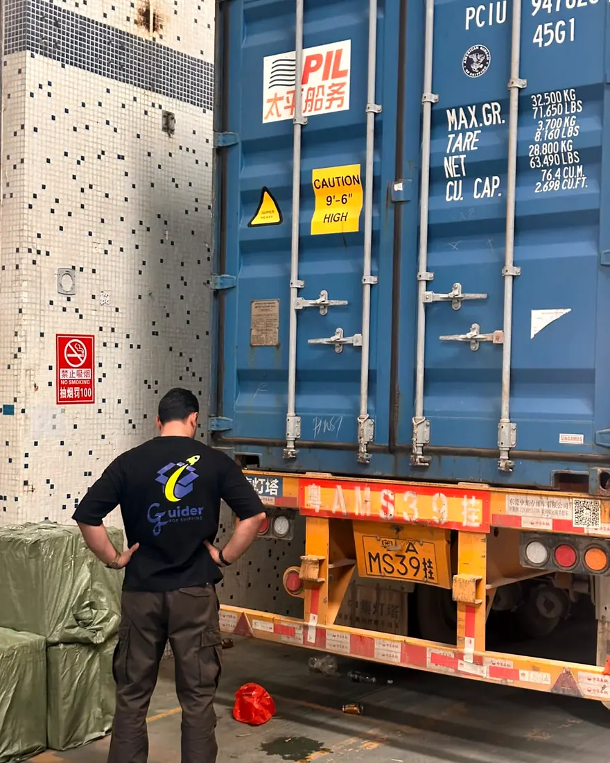 A GUIDER team member in a GUIDER shirt inspecting a sealed 40-foot container on a truck in Guangzhou