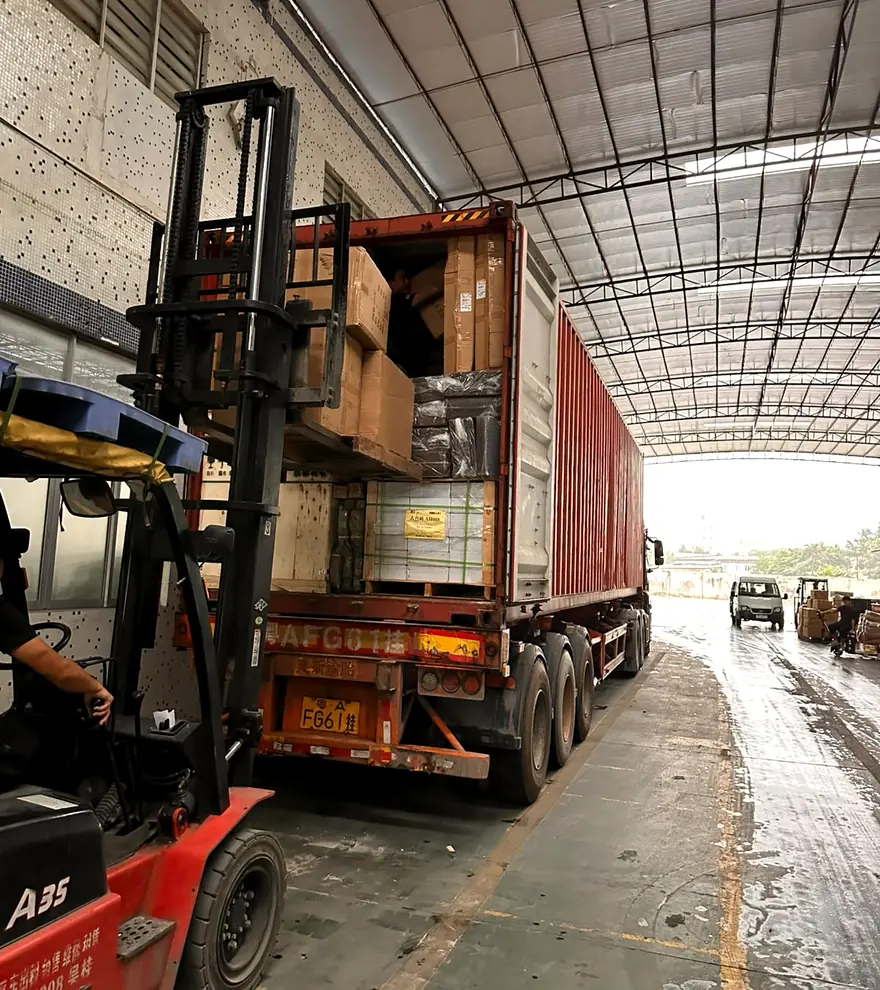 Forklift loading mixed cartons and crates from several customers into a shared container in Guangzhou